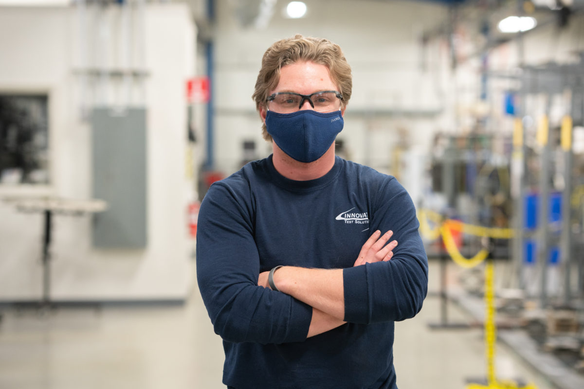 ITS safety precautions in place for employees and labs, a worker wearing safety glasses, facemask, and a dark blue shirt. 
