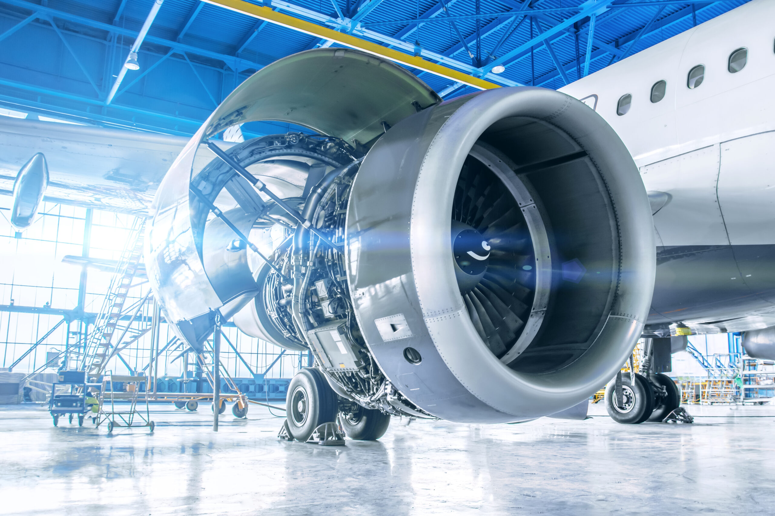 view of an airplane engine and wing in a hangar with sunlight streaming in the background