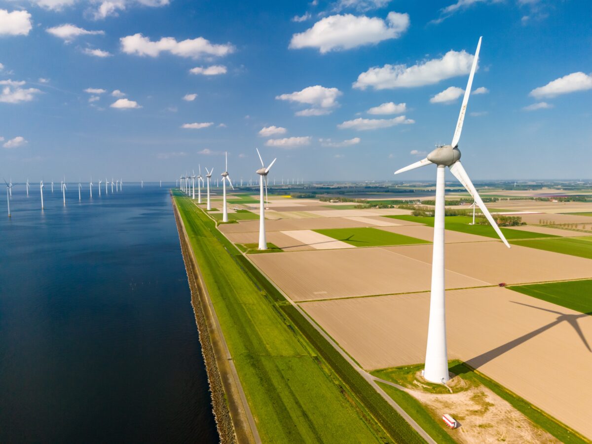 A view of onshore and offshore wind turbines, with engineering that relies on fatigue testing; blue skies and fluffy white clouds in the background